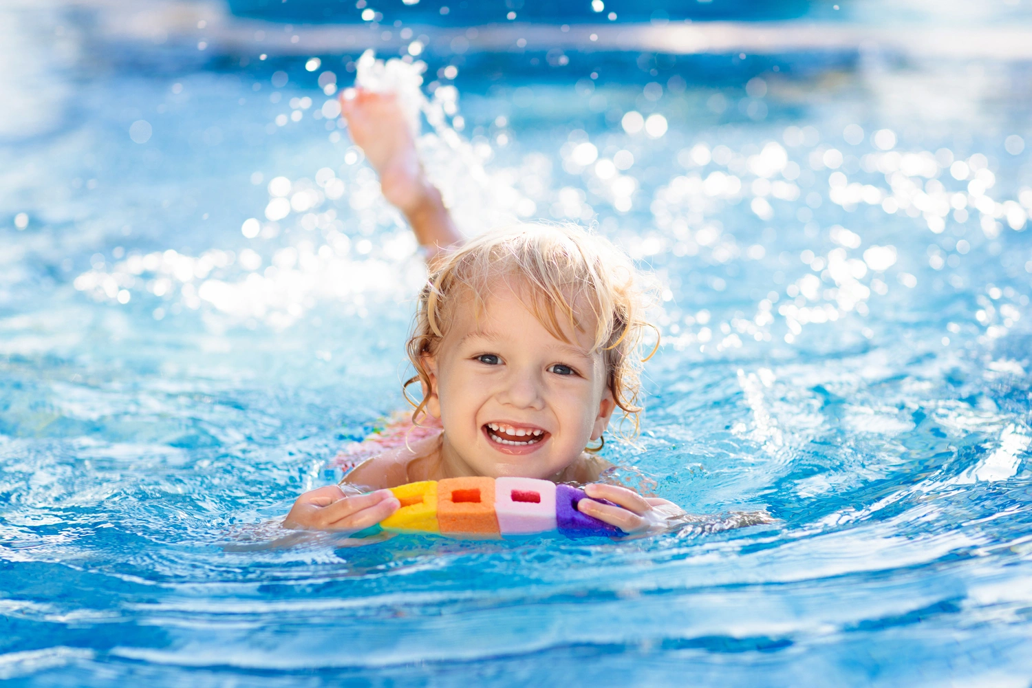 Child learning to swim in outdoor pool of tropical resort