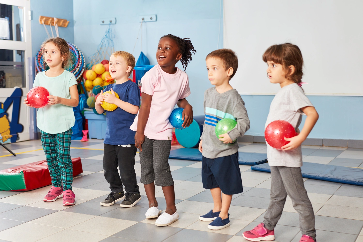 Group of kids in the gym in the international kindergarten with colorful balls