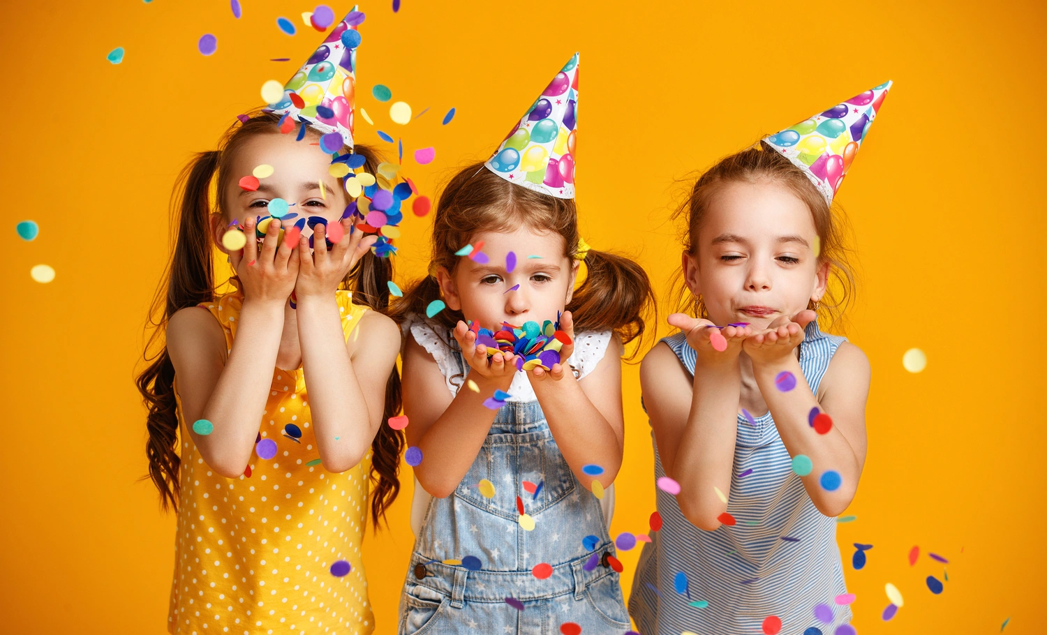 Happy birthday children girls with confetti on colored yellow background