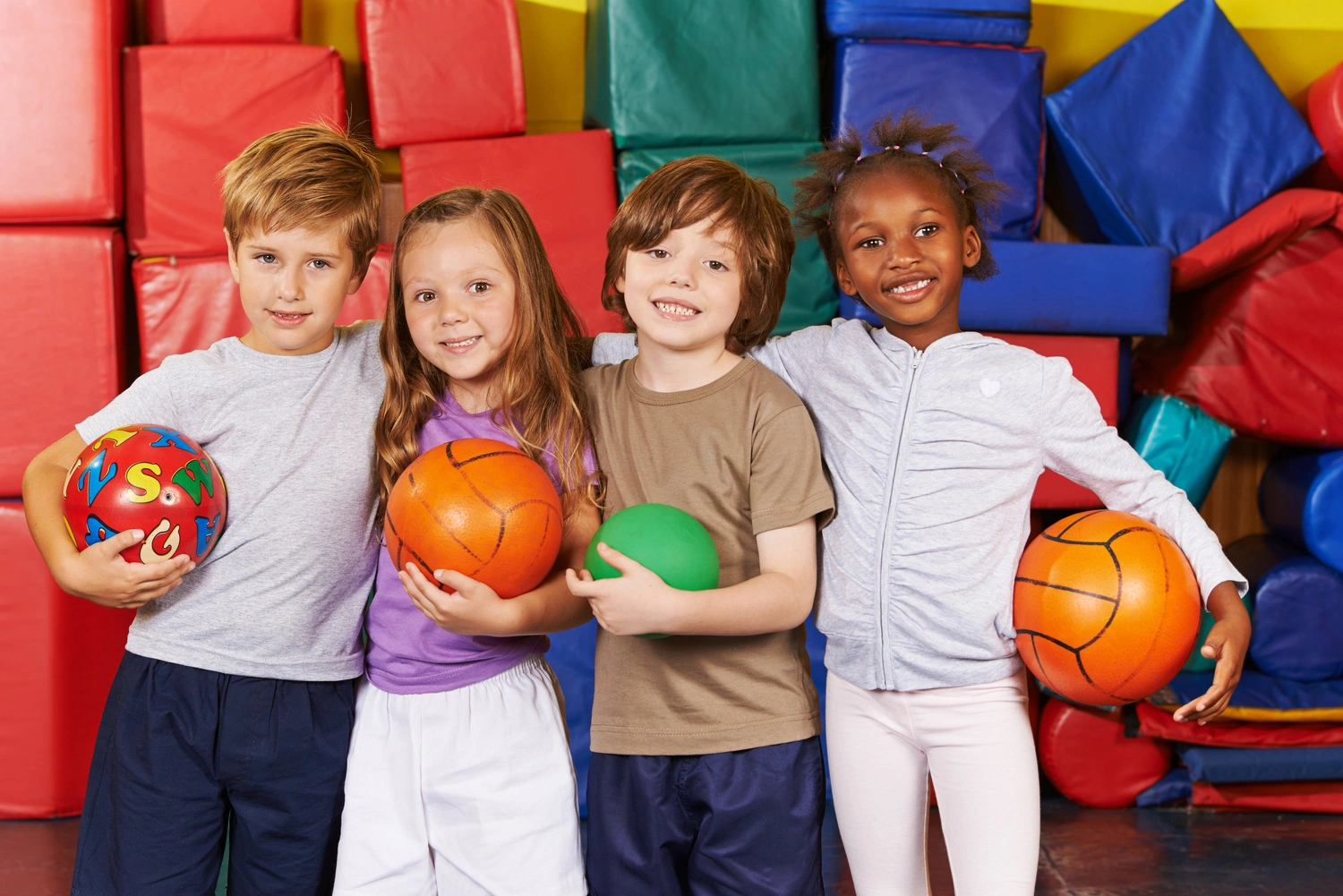 Happy children as team with different balls in a gym of a preschool