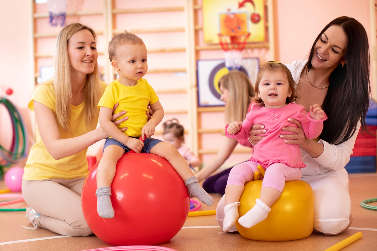 Mothers with babies doing exercises with gymnastic ball in gym