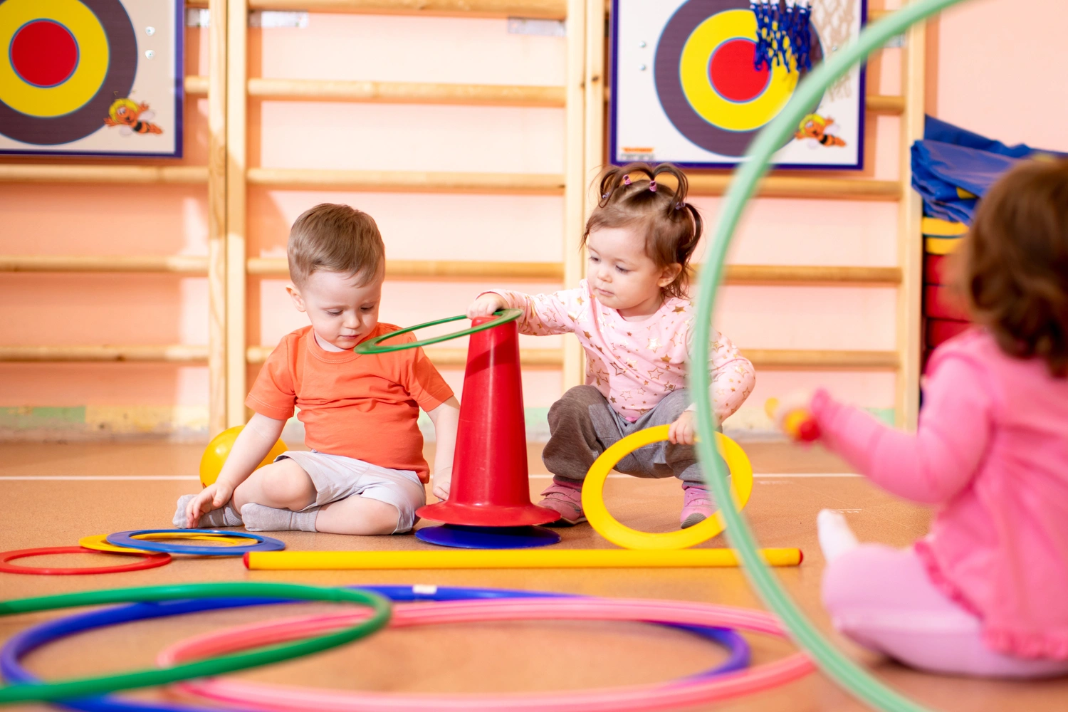 Nursery babies toddlers group play with rings in gym